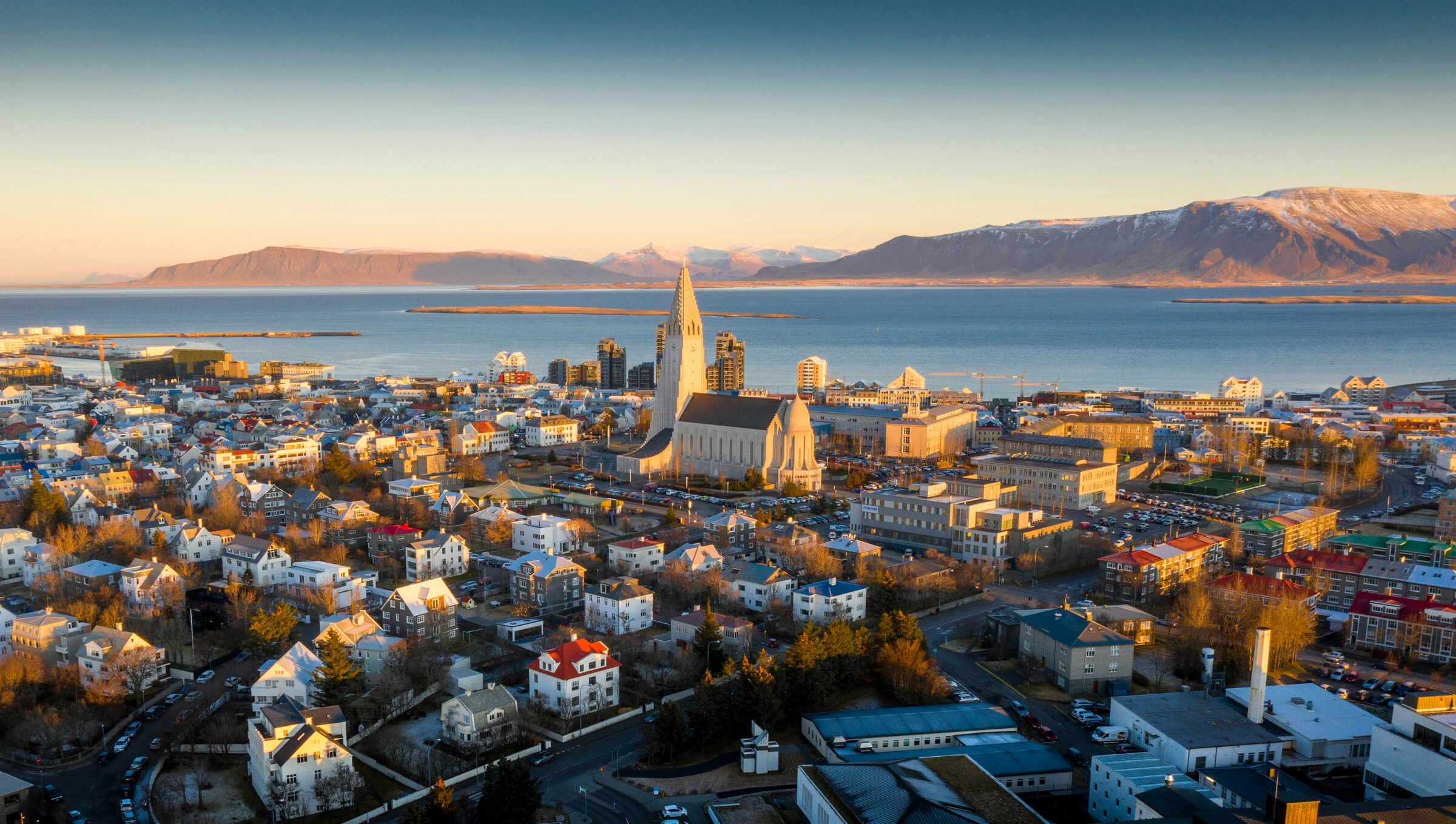 Reykjavík at sunrise, with Hallgrímskirkja church, the bay and snowy mountains